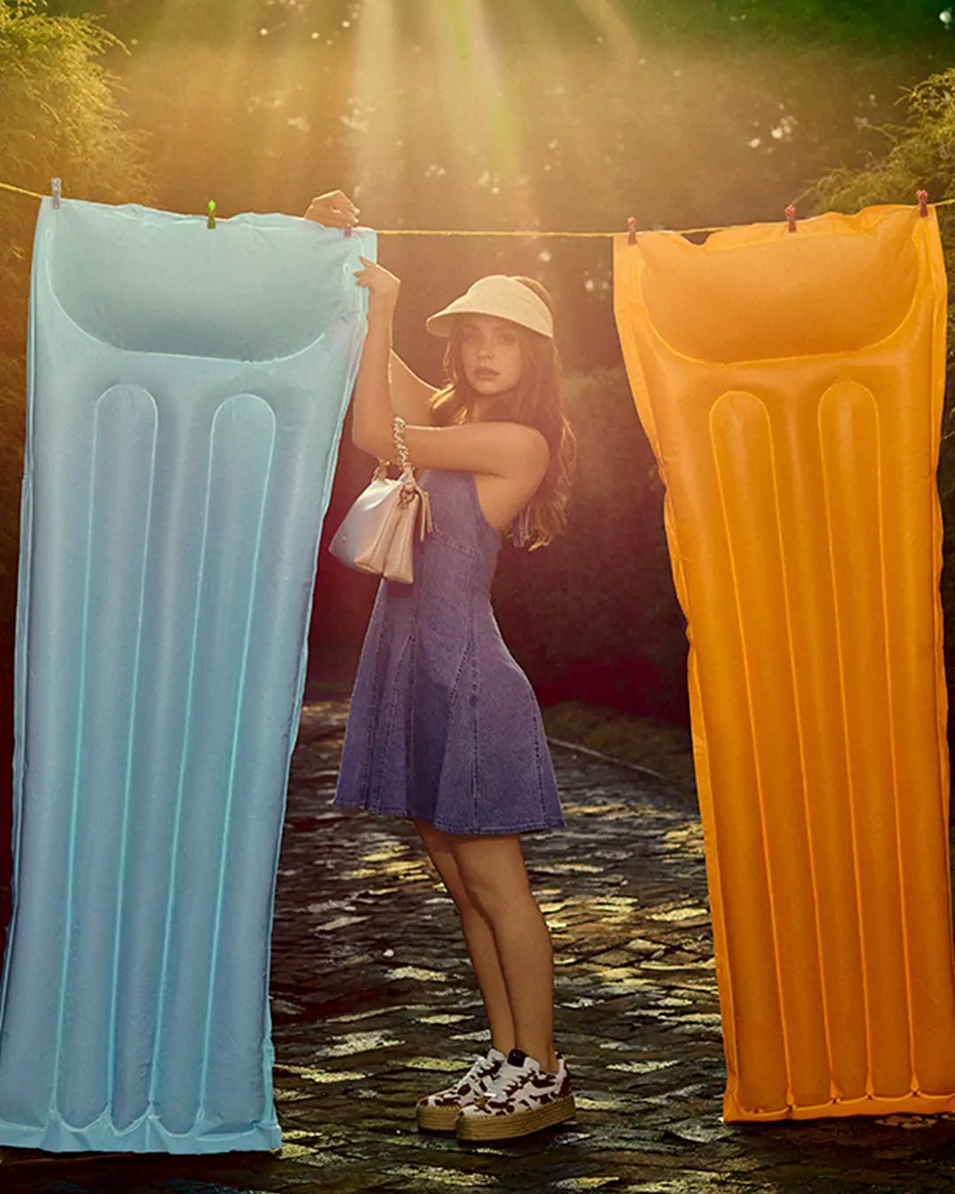 Mujer luce vestido corto de mezclilla, tenis chunky, bolsa de mano beige, look de verano divertido y casual para mujer.