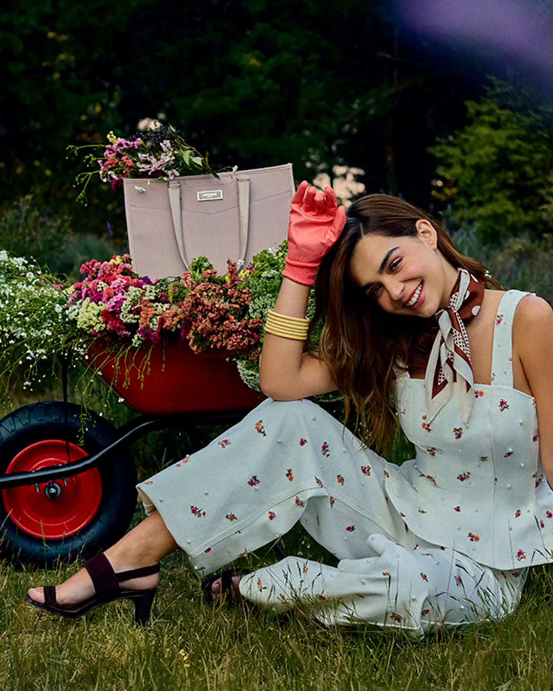 Mujer  luciendo conjunto de blusa y pantalón blanco floral, sandalias de tacón cafés Steve Madden con bolso tote beige destacado, look fresco, femenina y a la moda.